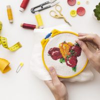 hands-sewing-cute-fruit-design-white-background